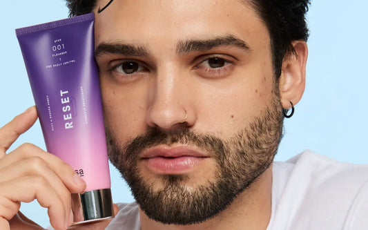 Male skincare model holding RESET cleanser 